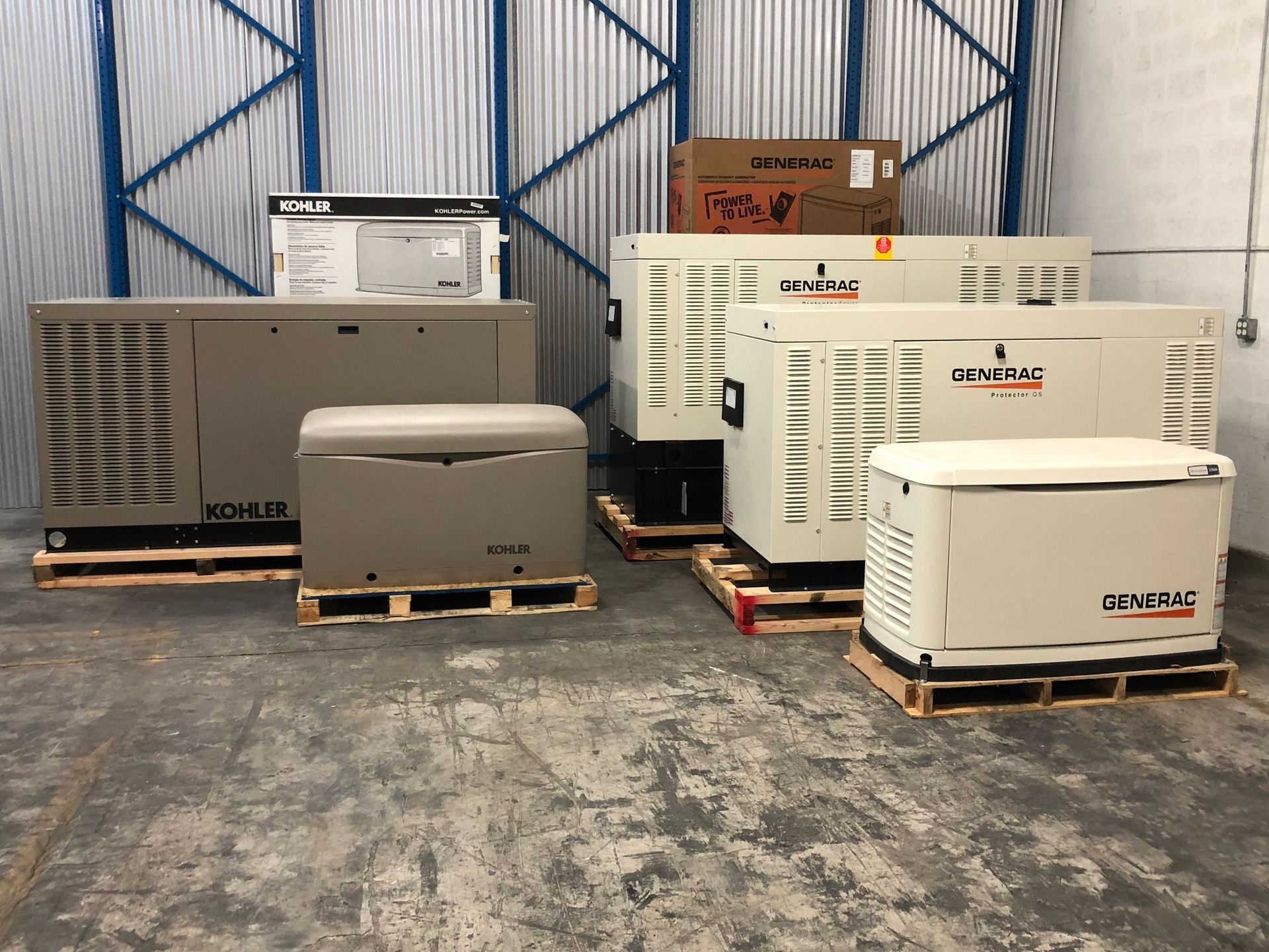 A group of generators are sitting on pallets in a warehouse.