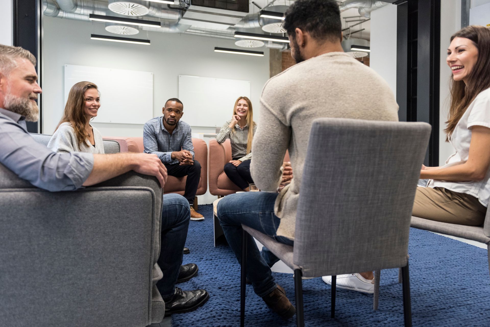 A family is laying on the grass together and smiling.