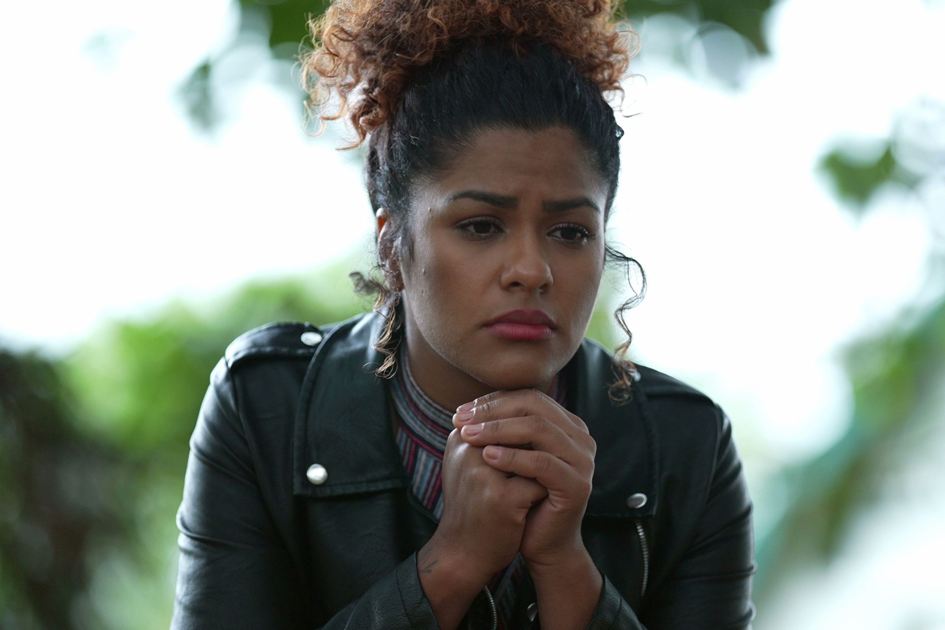 A woman is sitting on a couch with her head in her hands.