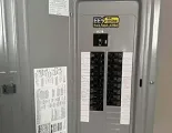 A grey electrical circuit breaker panel with a sticker for EES Electrical Solutions featuring a contact phone number.
