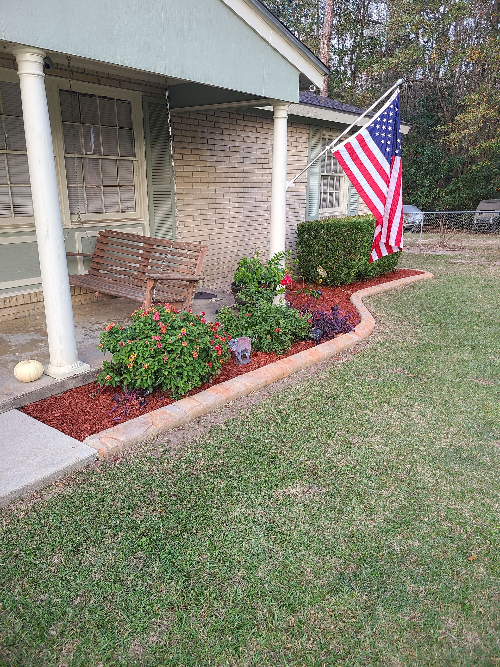 A large american flag is flying in front of a house.