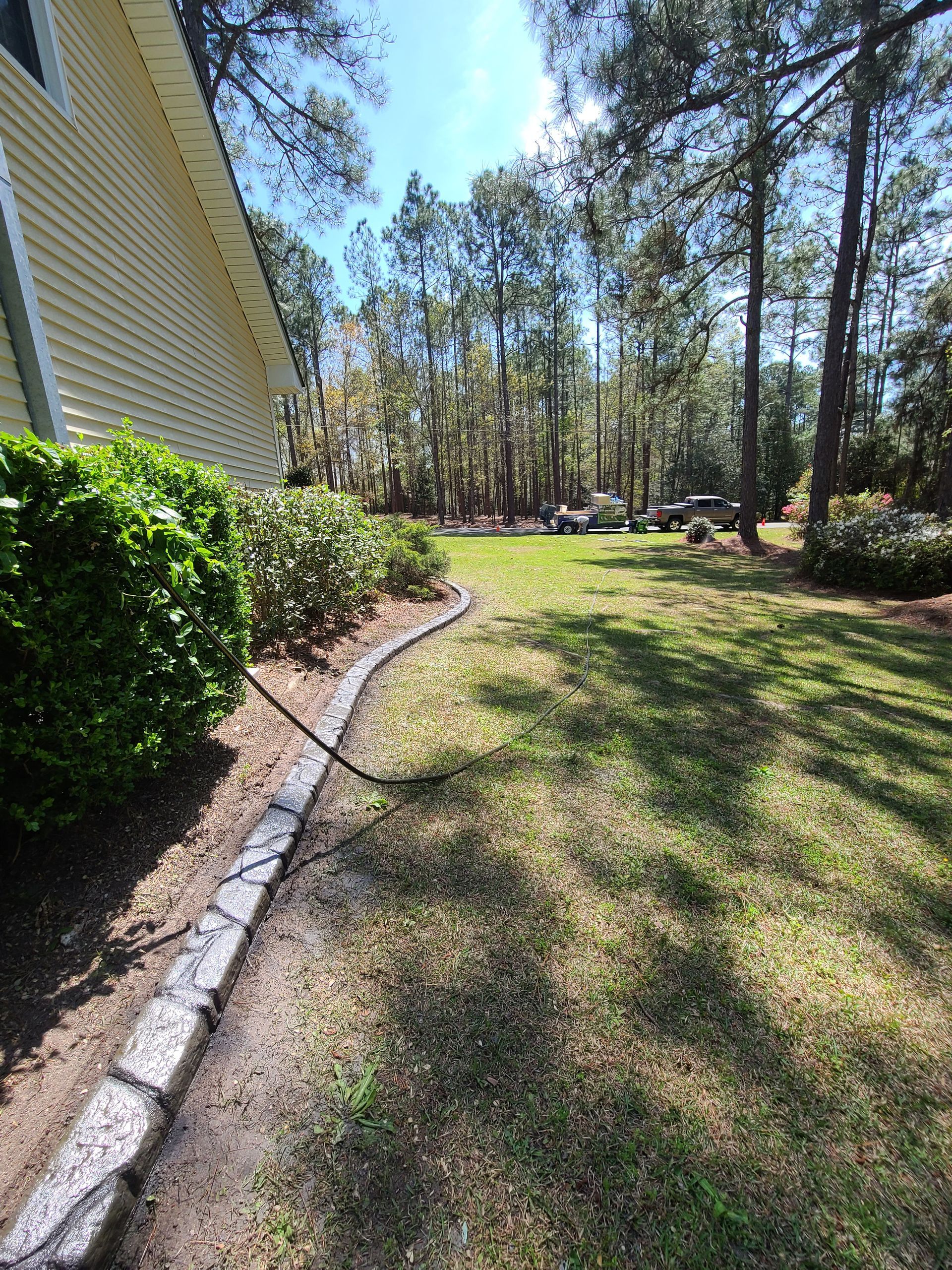 A lawn with a house in the background and trees in the background.