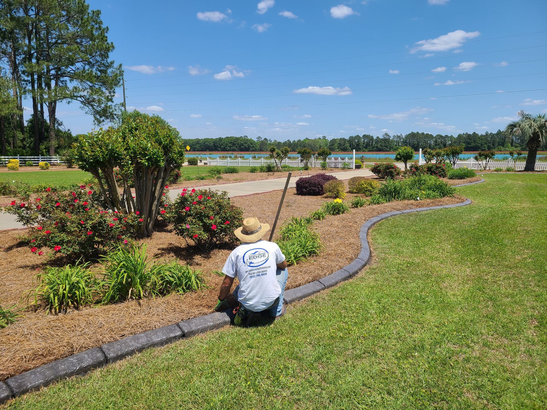 A man is kneeling on the grass in a garden.