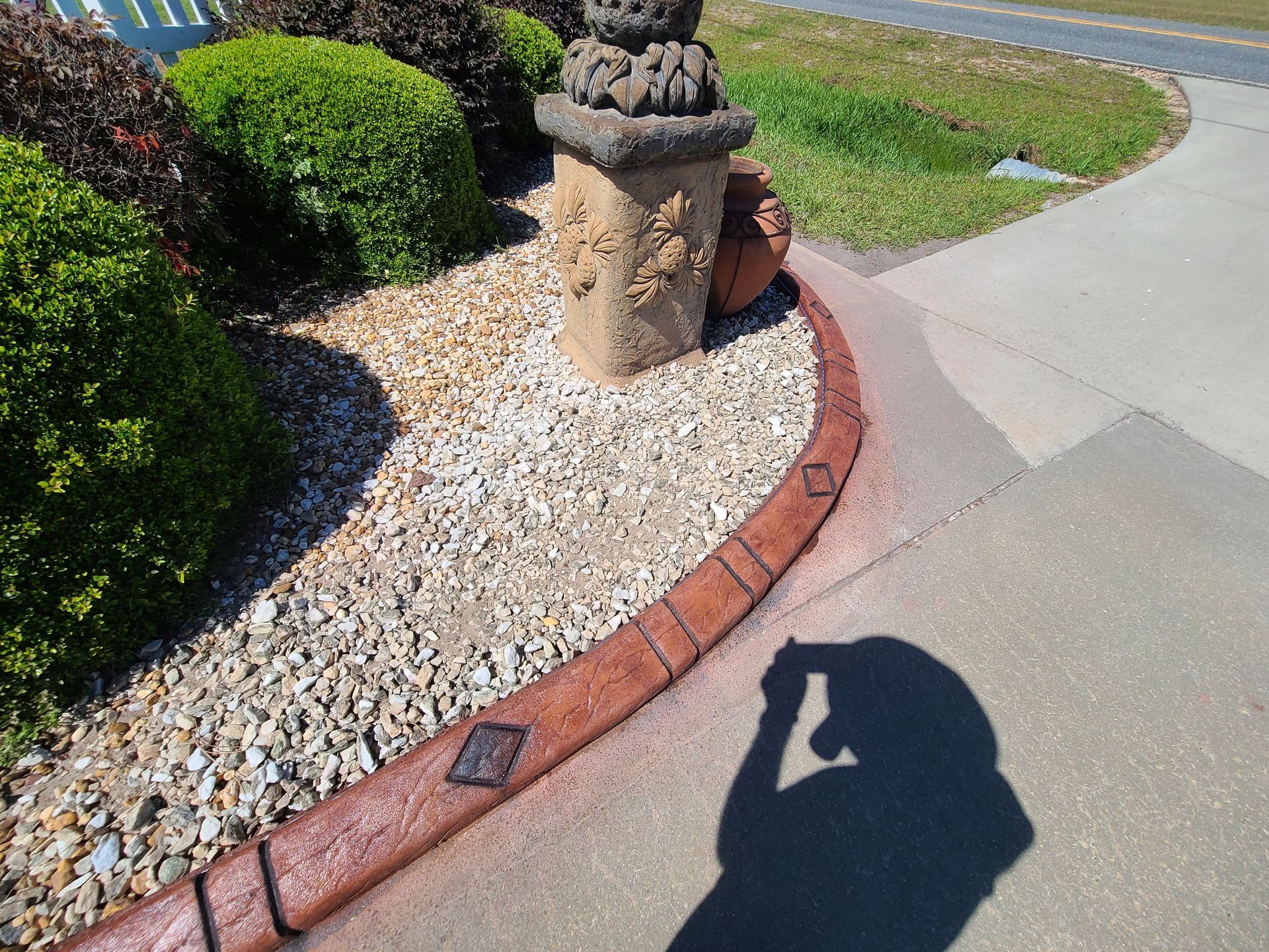 A person is taking a picture of their shadow on the sidewalk.