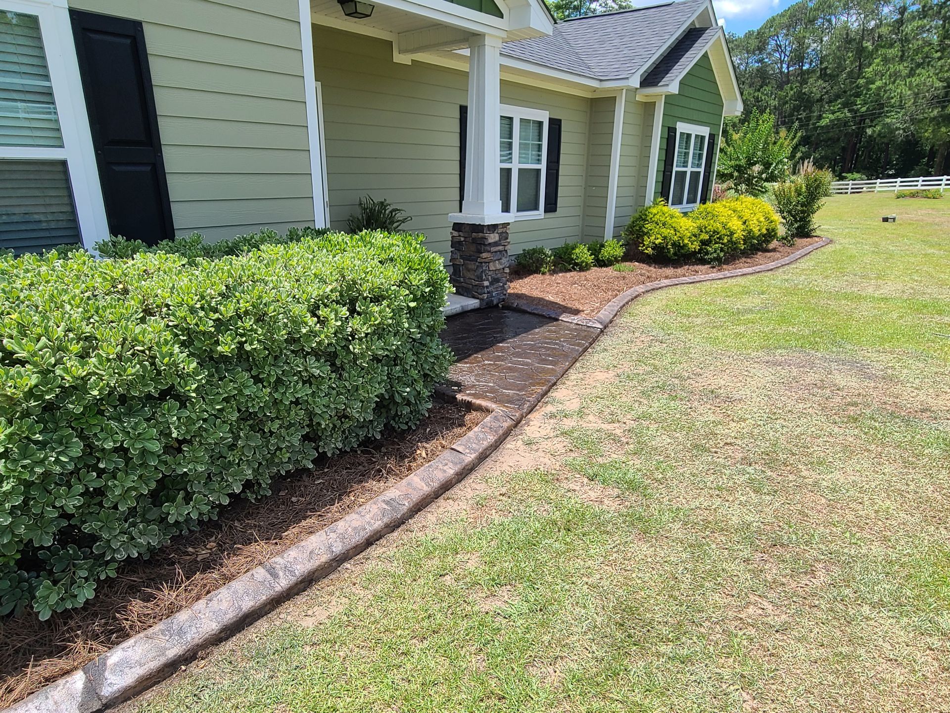 A house with a concrete curb in front of it.