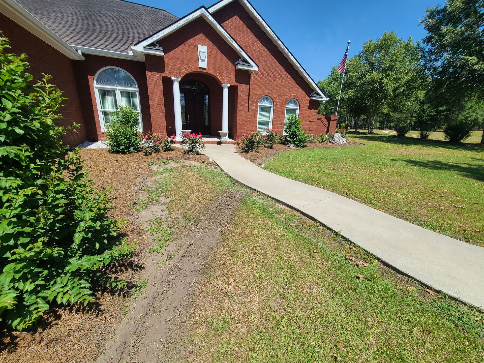 A brick house with a concrete walkway leading to it.