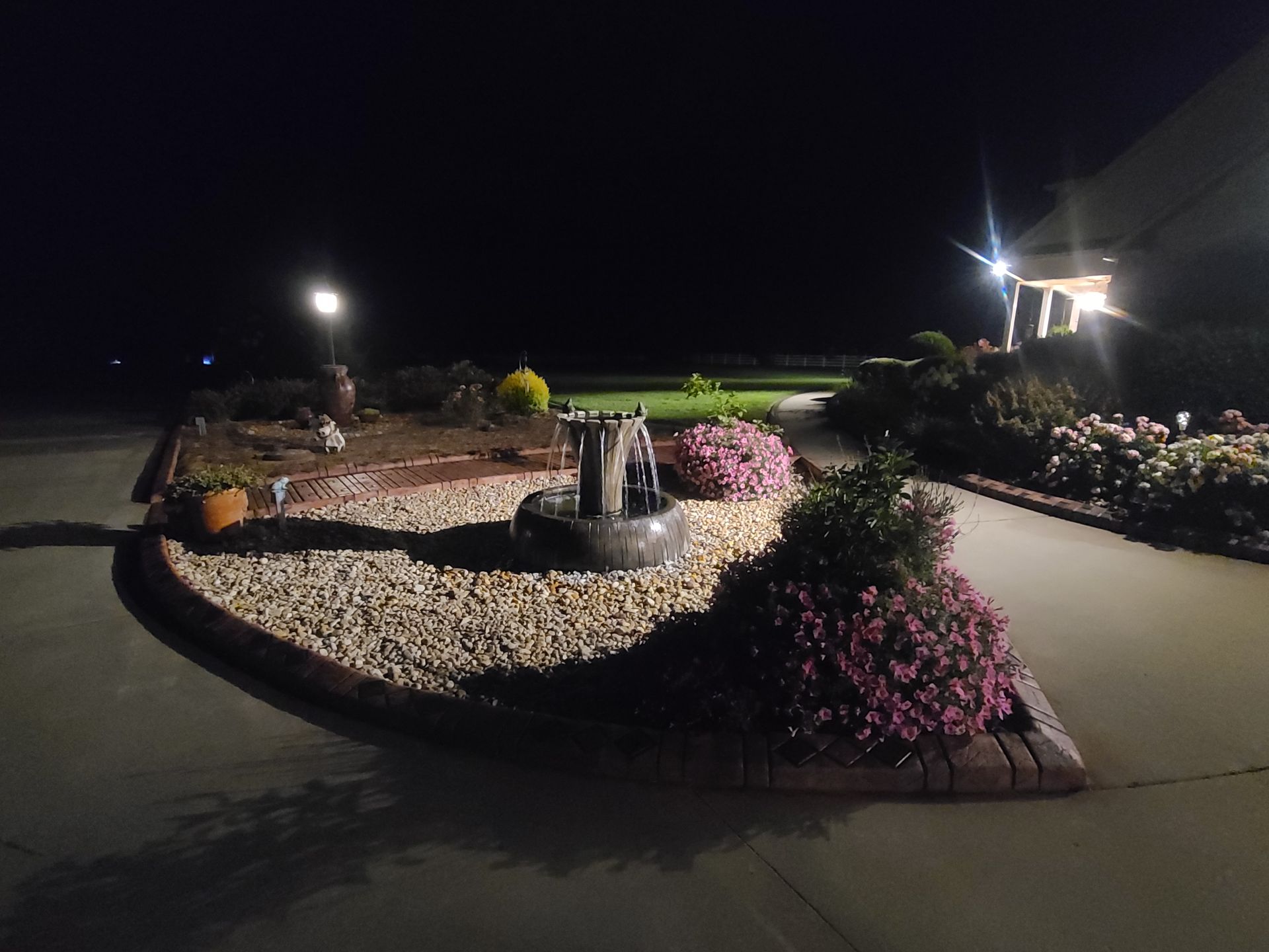 A fountain in the middle of a driveway at night