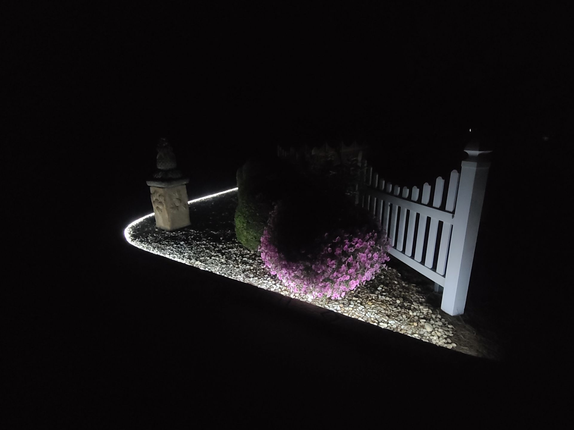 A white picket fence is lit up at night.
