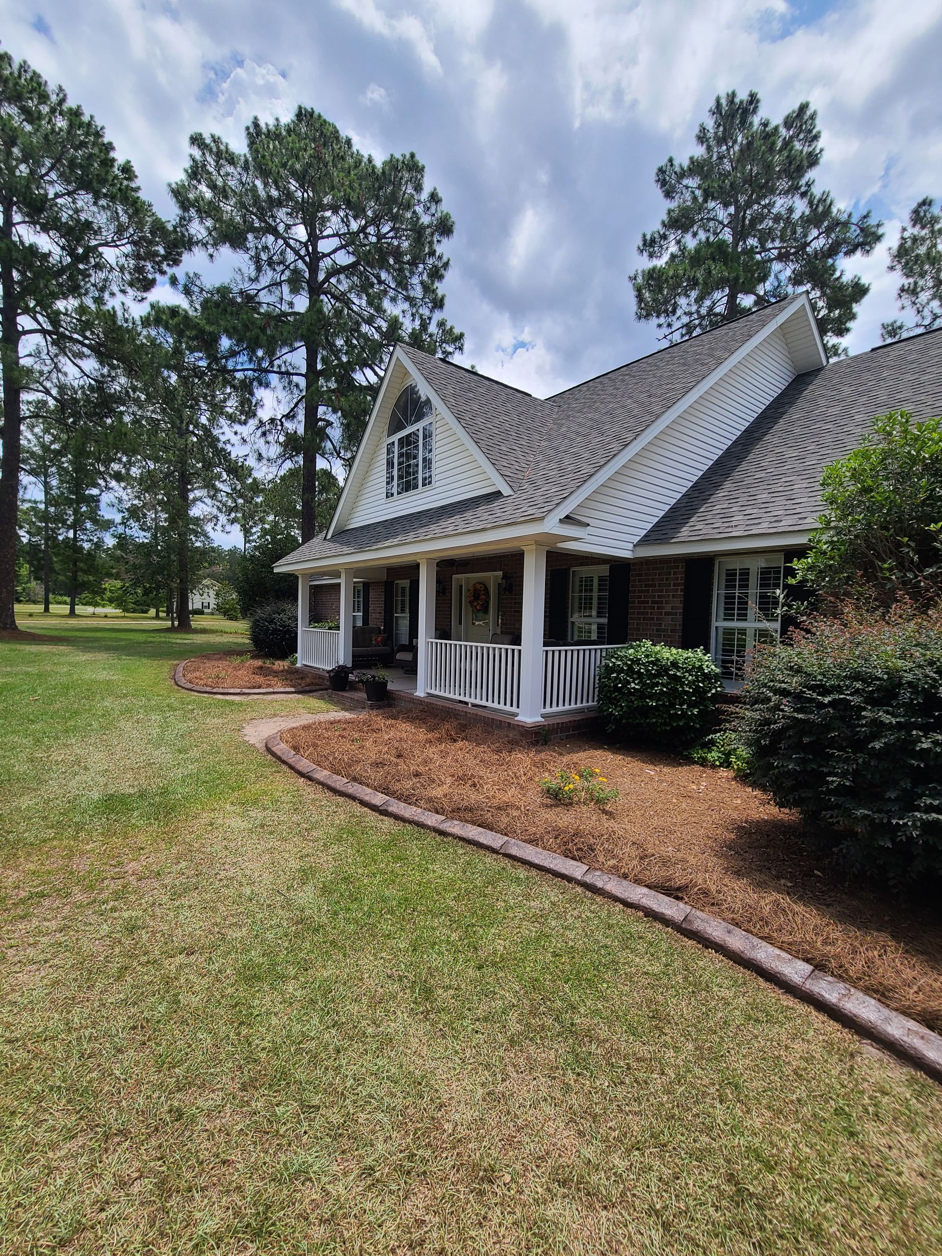 A large white house with a porch and trees in the background.