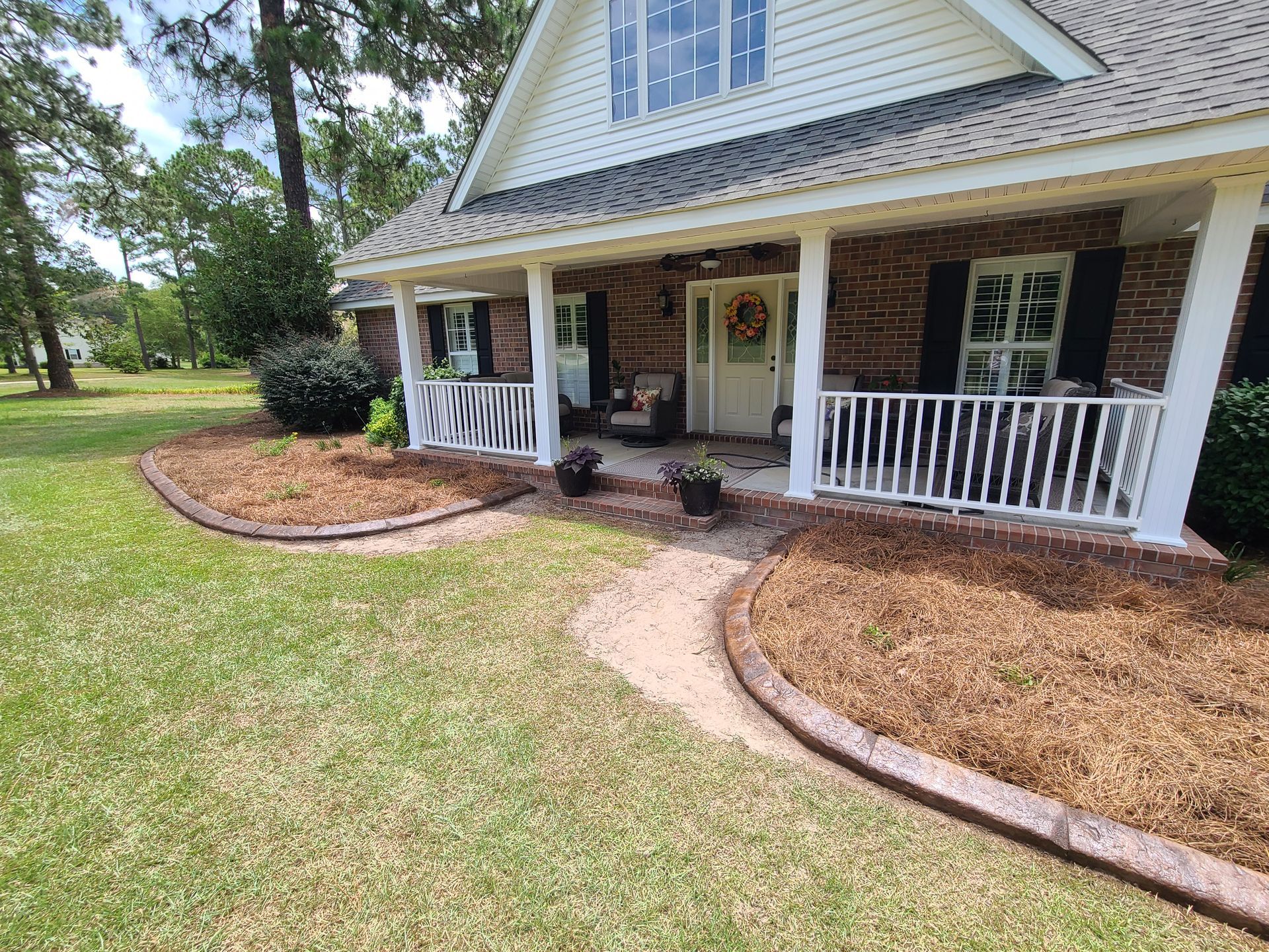 A brick house with a porch and a walkway leading to it.