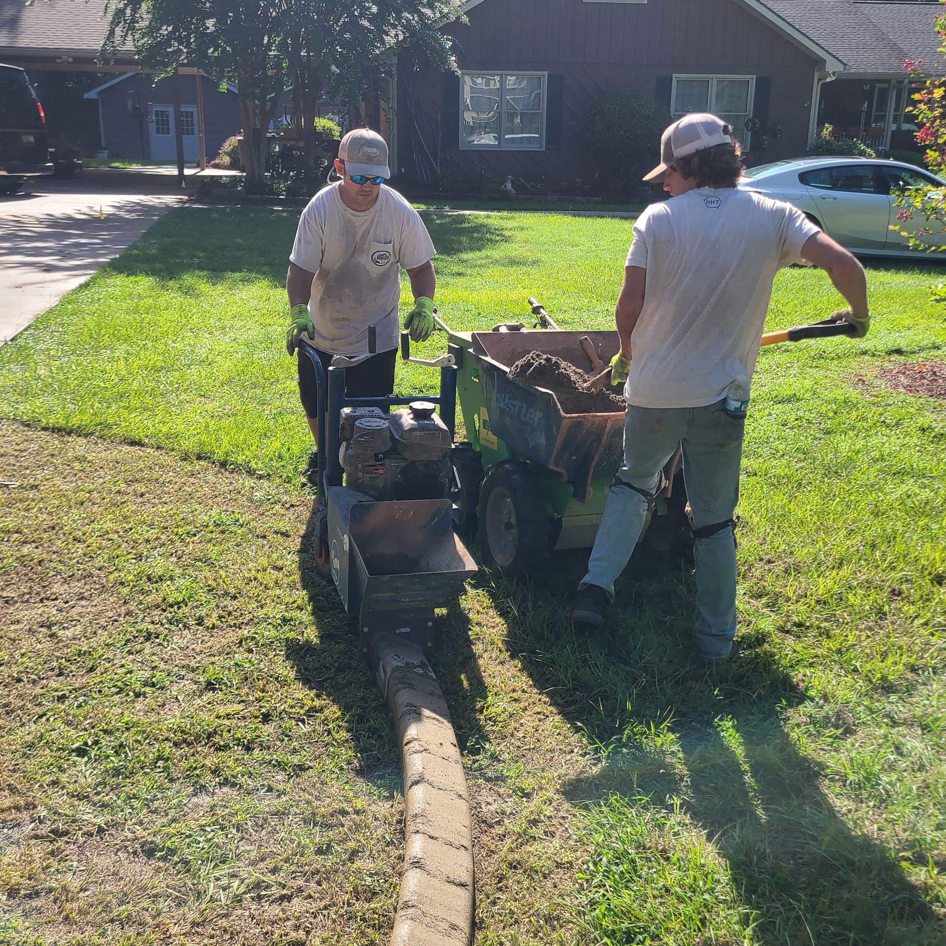 Two men pushing a cart full of dirt in front of a house
