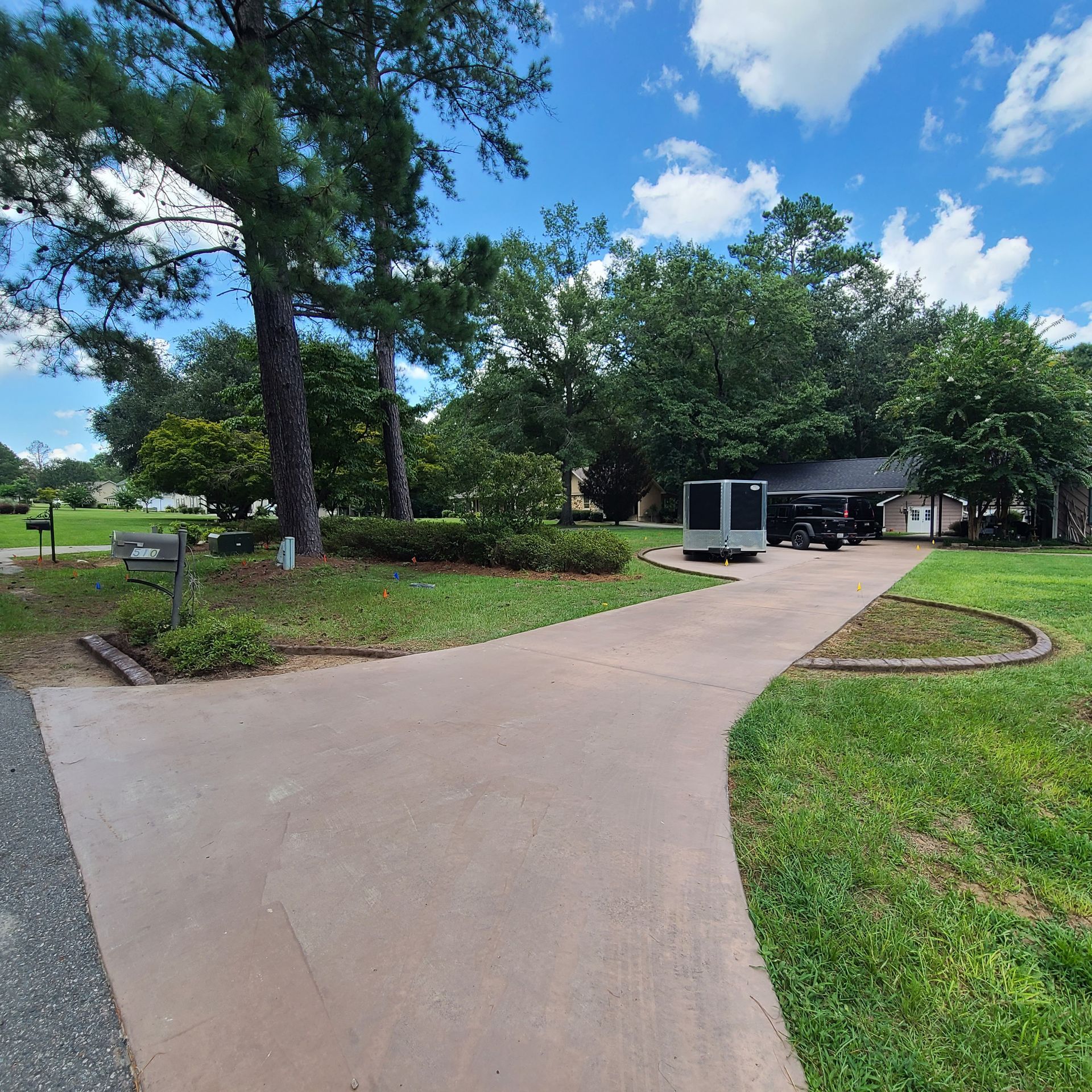A driveway leading to a house surrounded by trees and grass