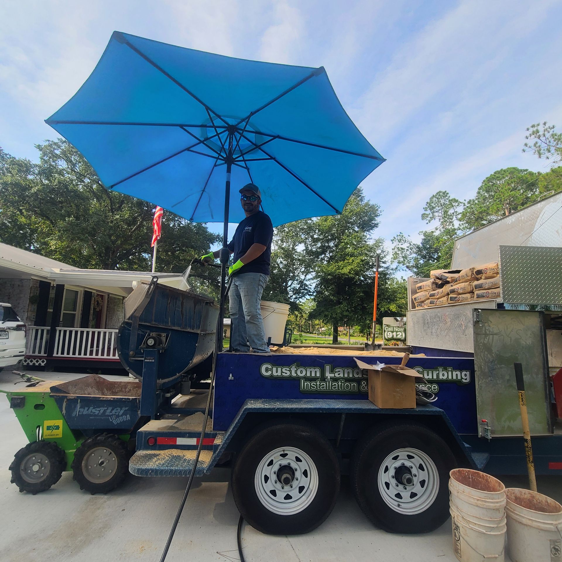 A man is standing on a trailer that says custom lawns