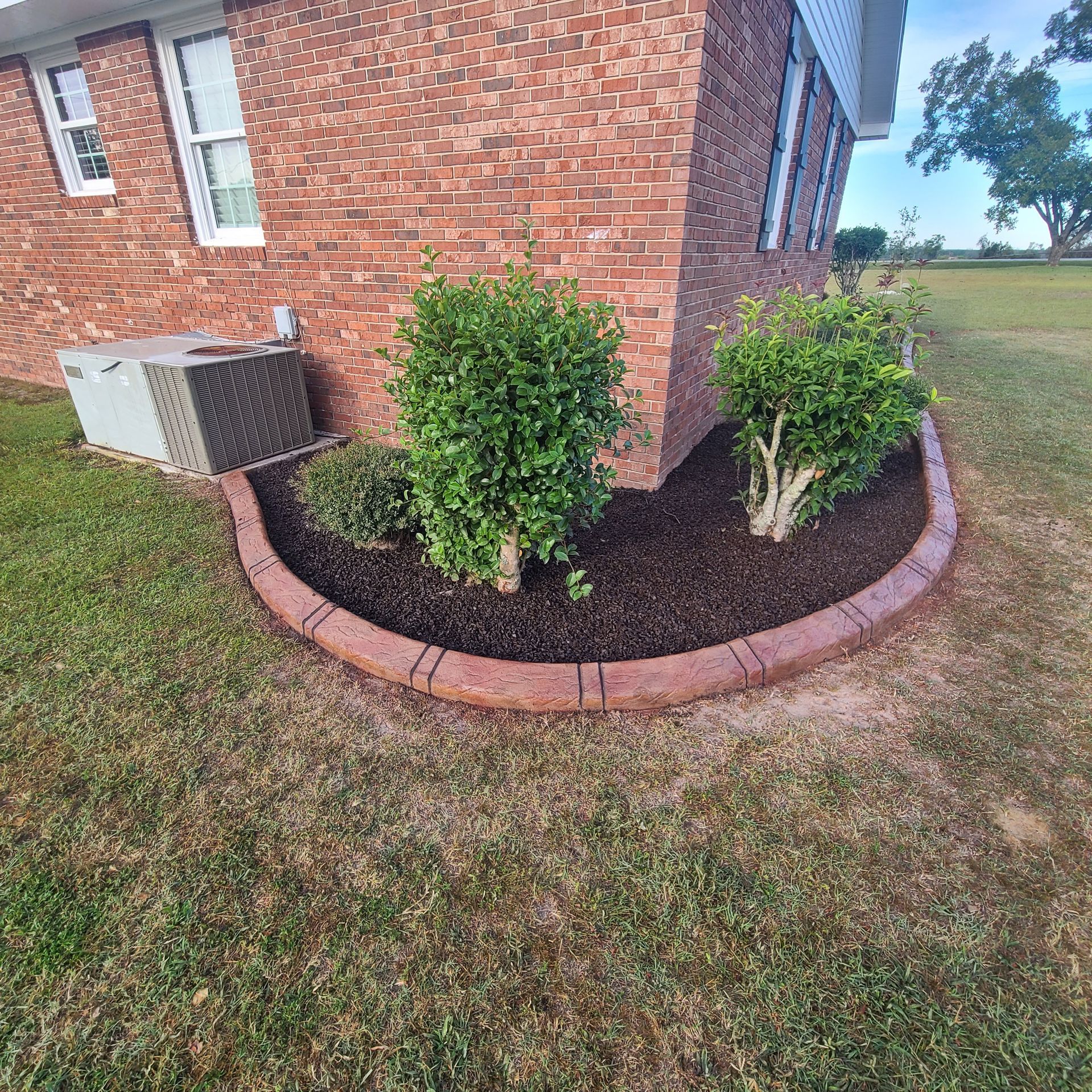 A brick house with a circular garden in front of it.