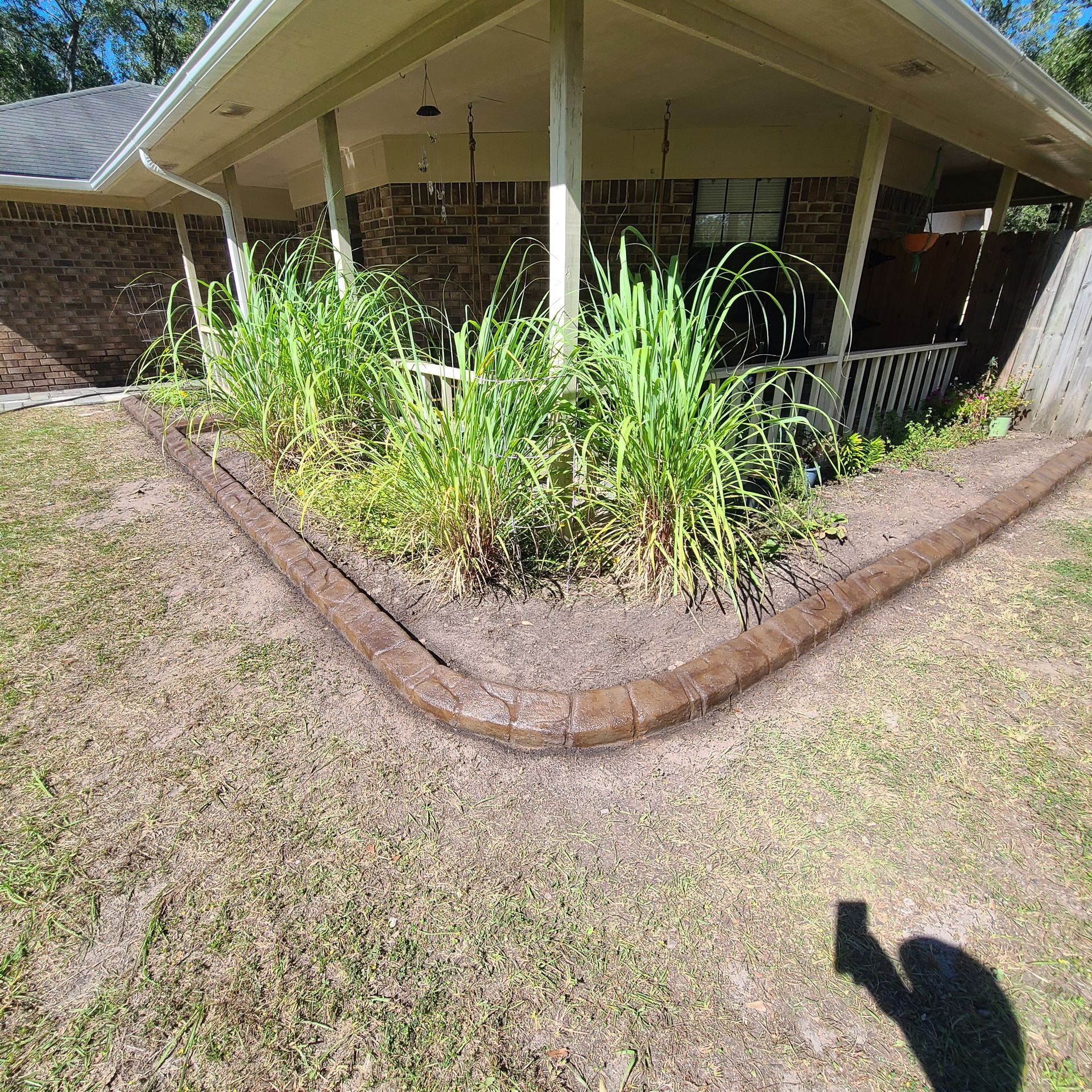A shadow of a person is cast on the grass in front of a house.