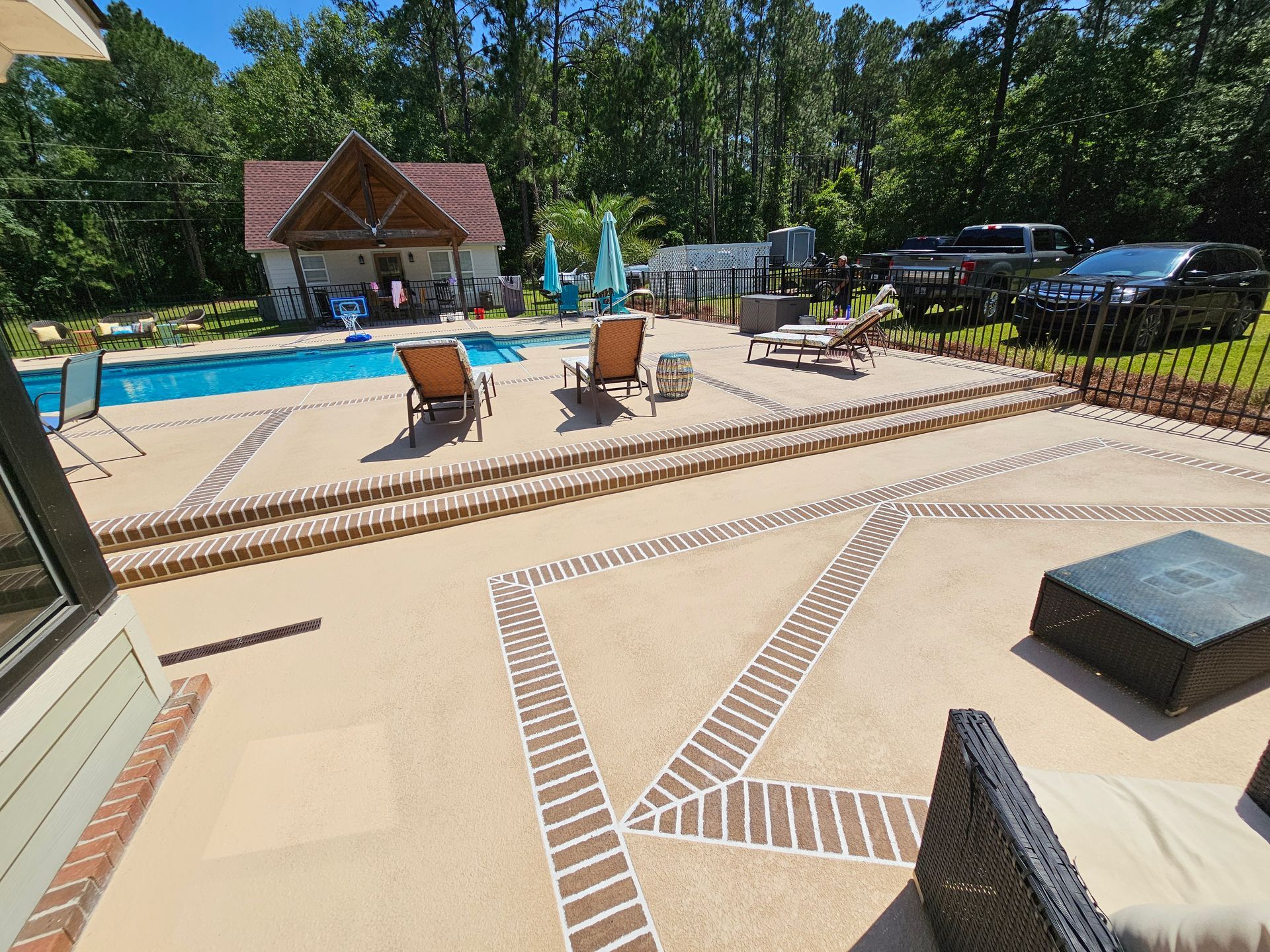 A patio with chairs and a swimming pool in the background