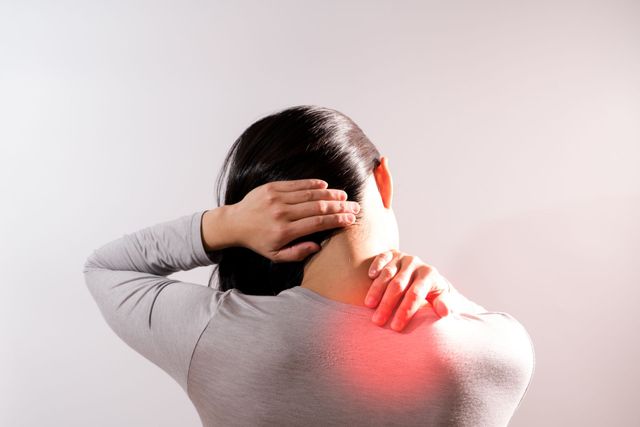A woman is holding her neck in pain with a red spot on her back.