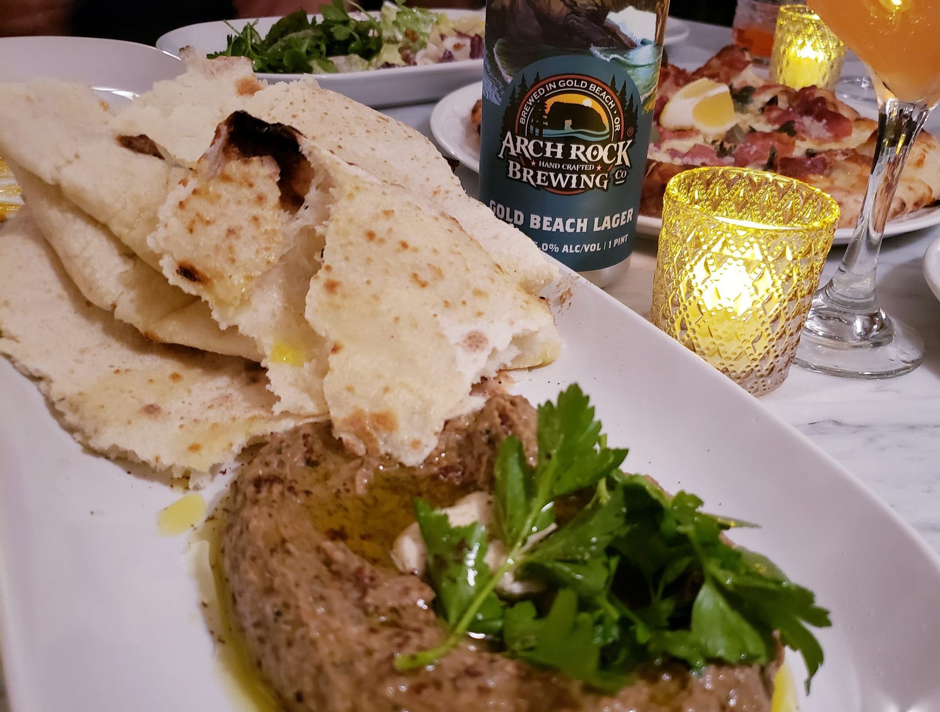 A Plate of Food with A Bottle of Beer in The Background