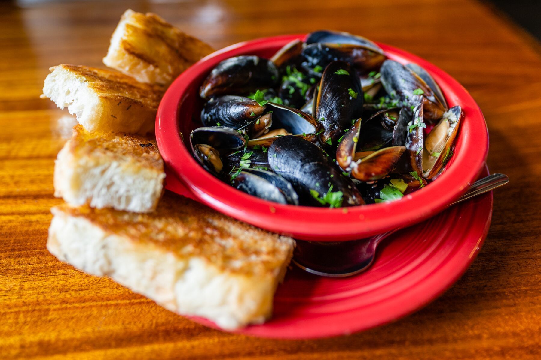 Bowl of Mussels and Bread on A Red Plate on A Wooden Table