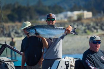 Man is Holding a Large Fish While Standing on A Boat