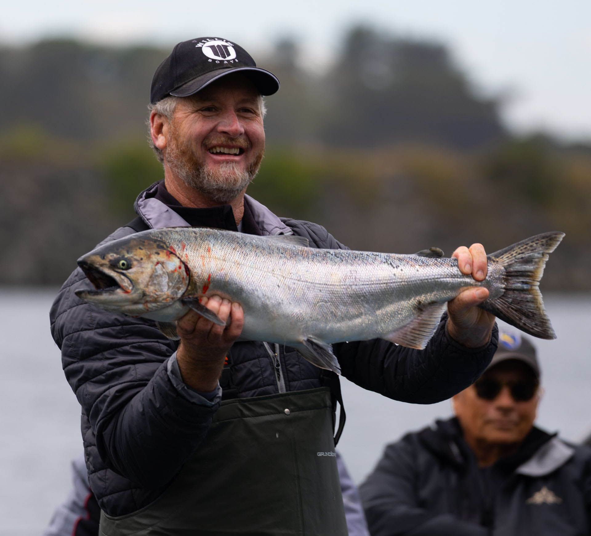 A man in a black hat is holding a large fish in his hands