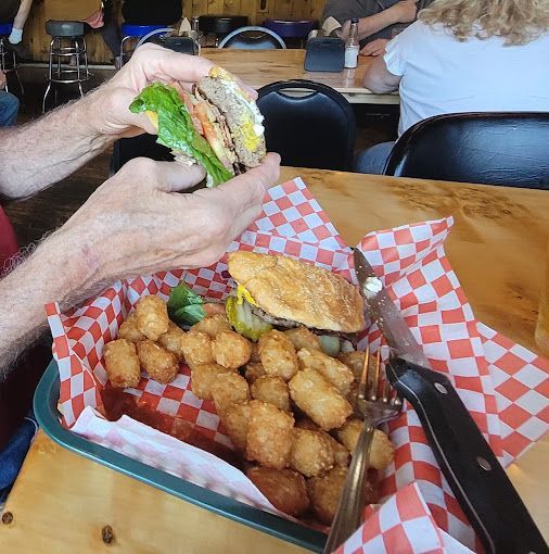 Person Is Taking a Bite of A Hamburger from A Basket of Food