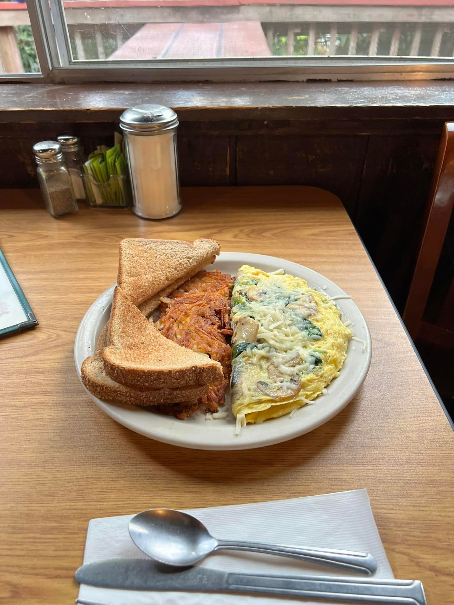 A Plate of Food with Toast , Eggs , and Hash Browns on A Wooden Table