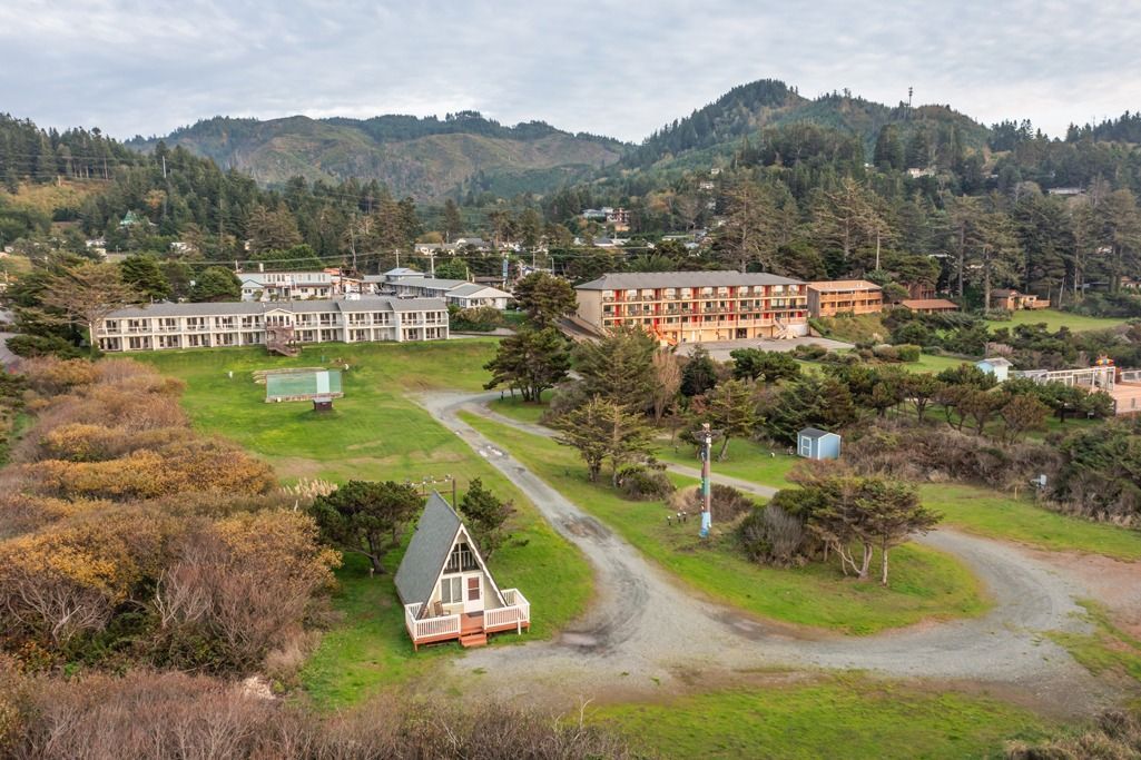 Aerial View of A Buildings in The Middle of A Grassy Field with Mountains in The Background