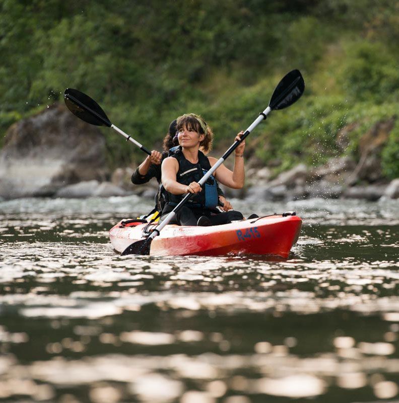 2 people kayaking down river in red kayak