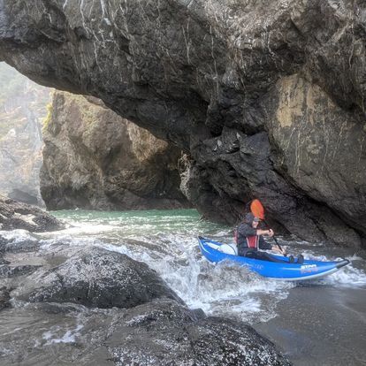 Person in A Blue Kayak Is Paddling Through a Cave in The Water