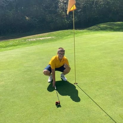 Man Squatting Down on A Golf Course Holding a Golf Club