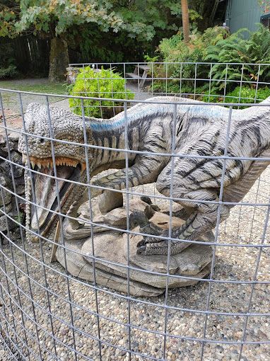 Statue of A Dinosaur Behind a Wire Fence