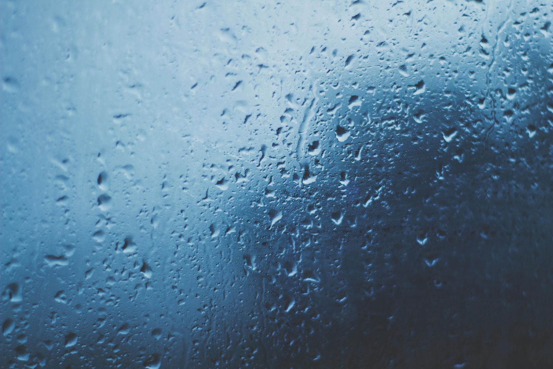 Raindrops on a window; blue and gray tones.