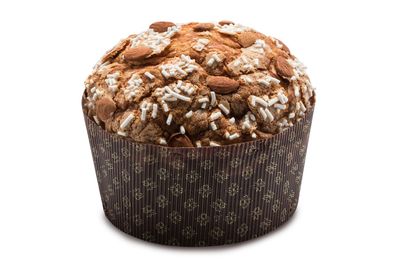 Un panettone decorato con mandorle e granella di zucchero, in un pirottino di carta marrone decorato su sfondo bianco.