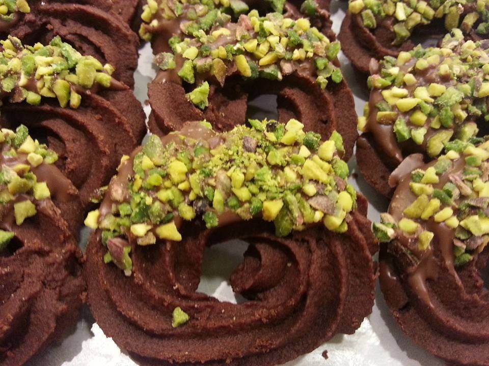 Primo piano di biscotti decorati con cioccolato e pistacchi verdi tritati, disposti uno accanto all'altro.