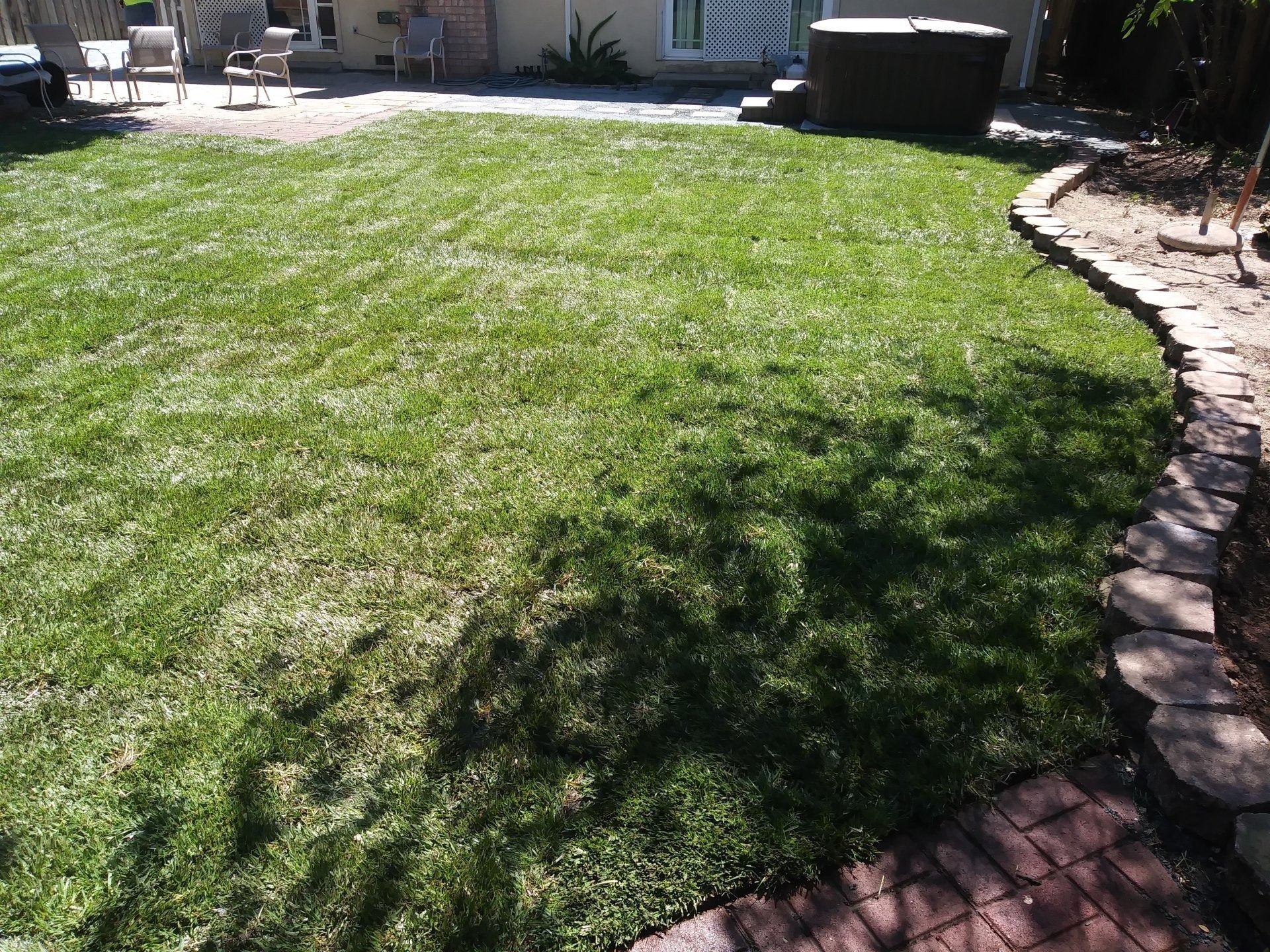 A lush green lawn with a hot tub in the background