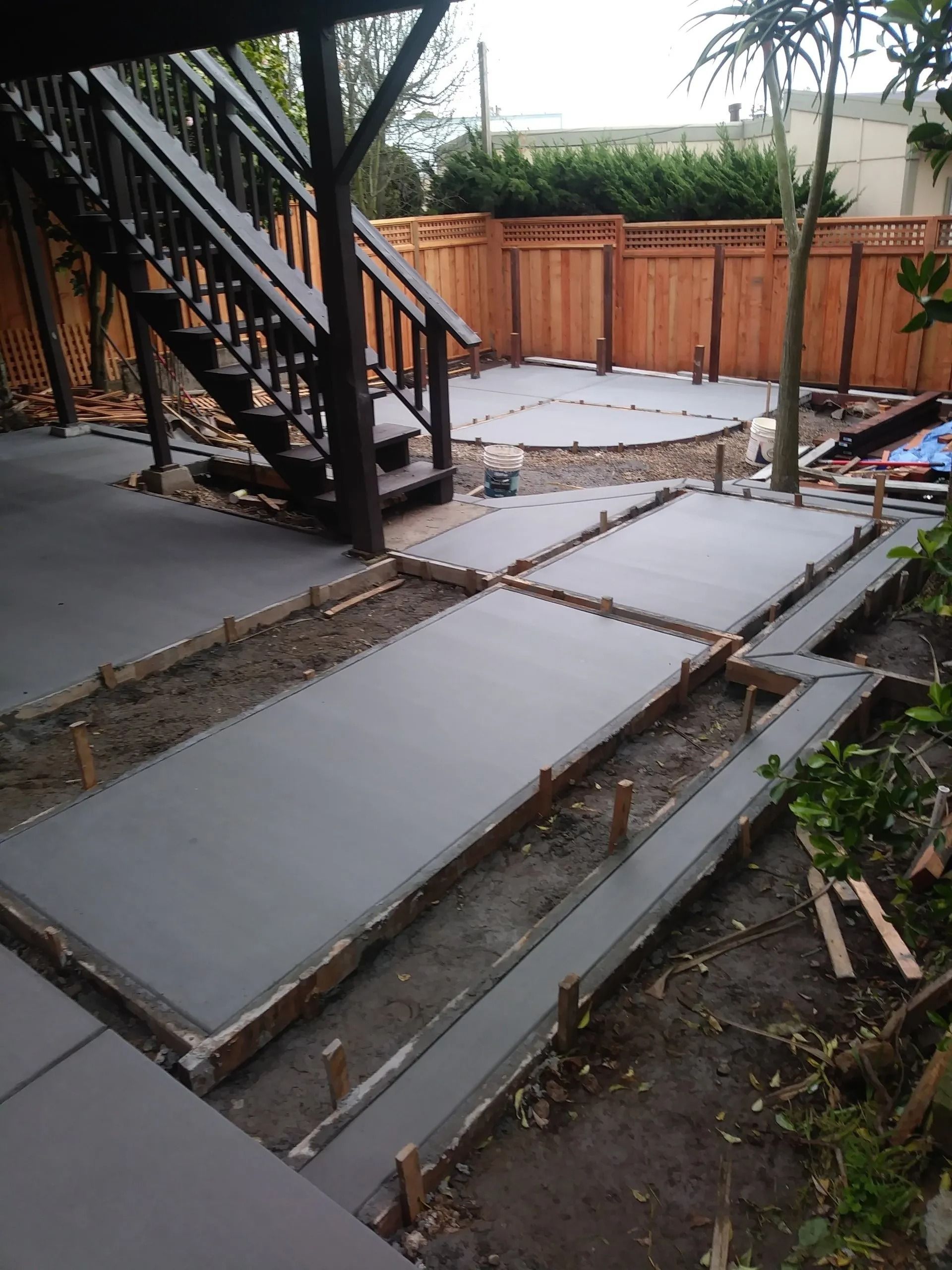 A concrete walkway is being built in a backyard with stairs.