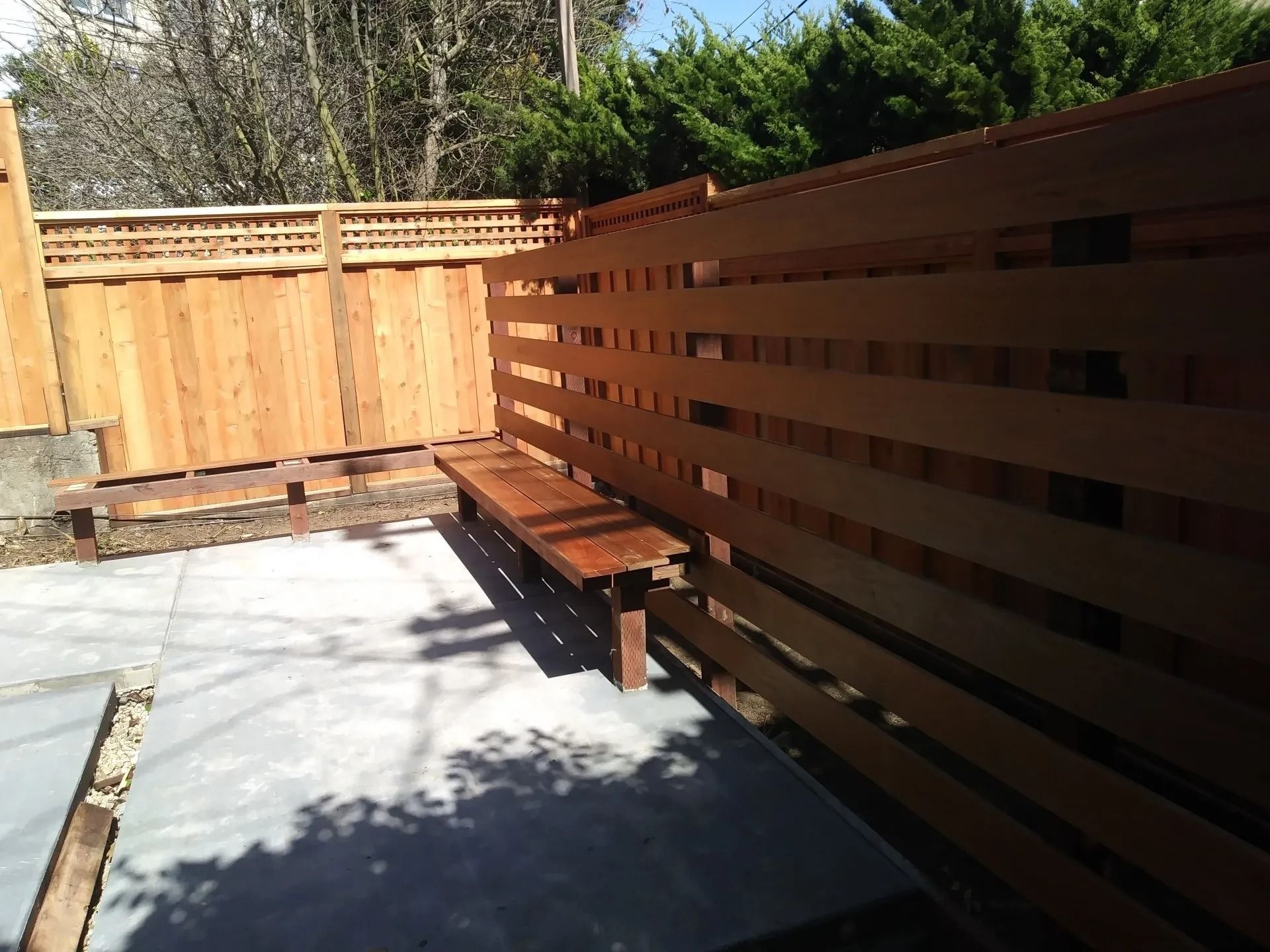 A wooden fence with a bench in front of it