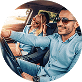 Man and woman wearing sunglasses inside car, sun shining outside, man driving car with smile | Leonardi Automotive