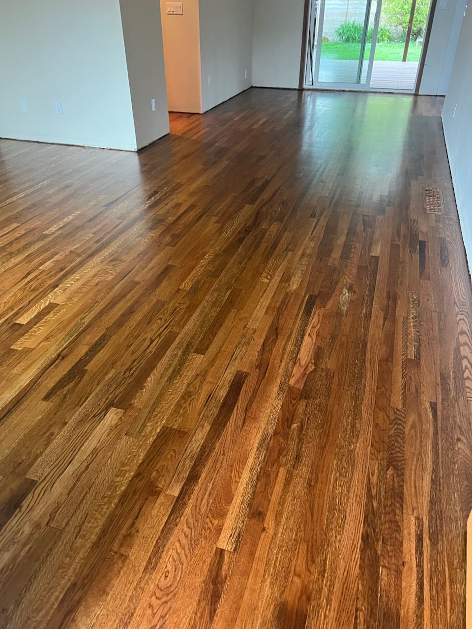 Empty room with dark wood floors and a large window in natural light