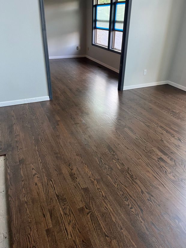 Empty room with dark wood floors and a large window in natural light