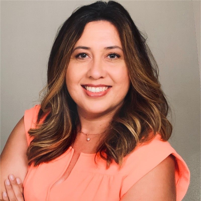 A woman in an orange shirt is smiling for the camera