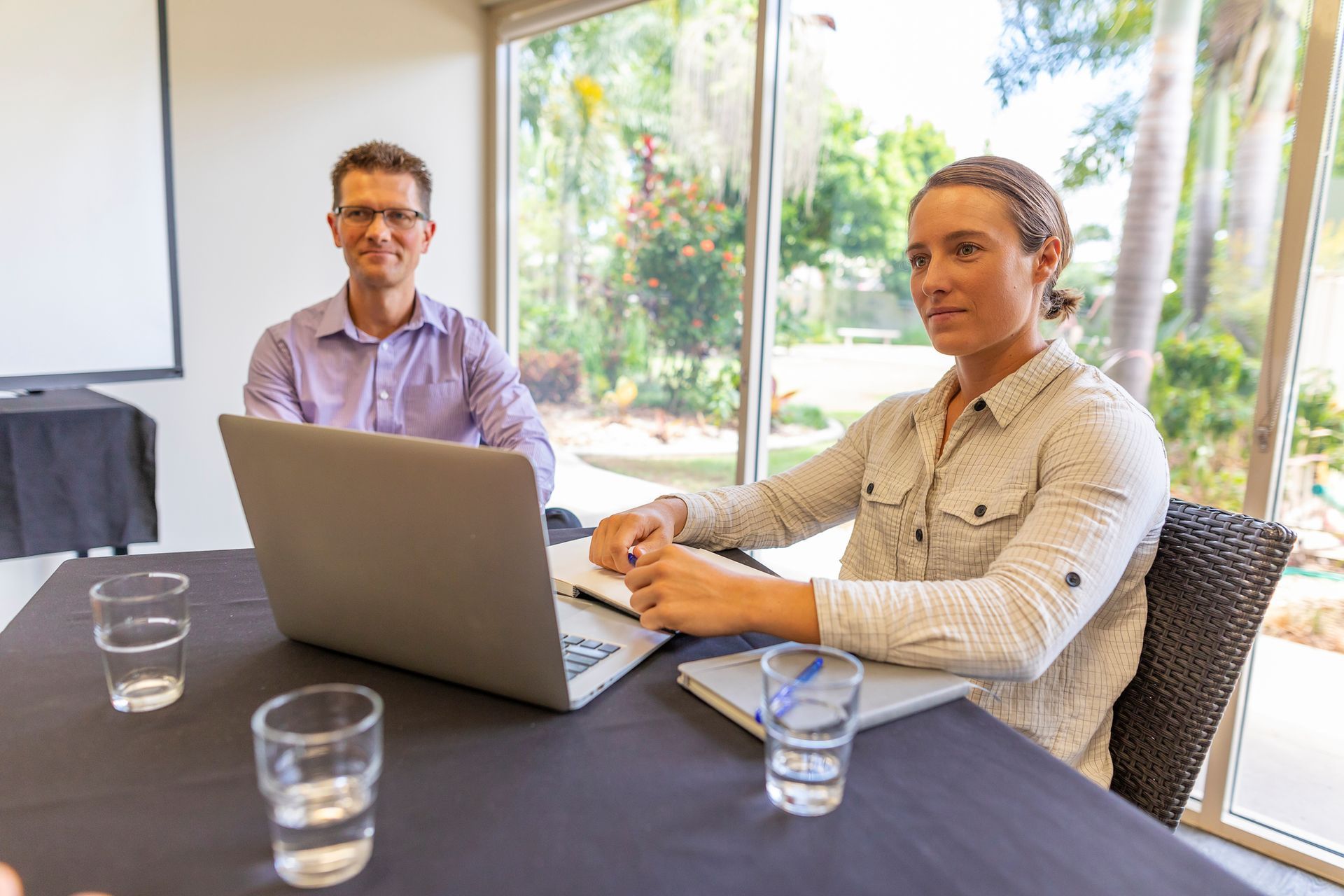 A man and a woman are sitting at a table with a laptop.