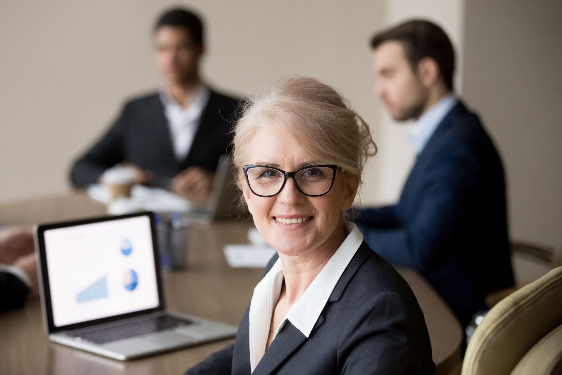 A woman is sitting at a table in front of a laptop computer.
