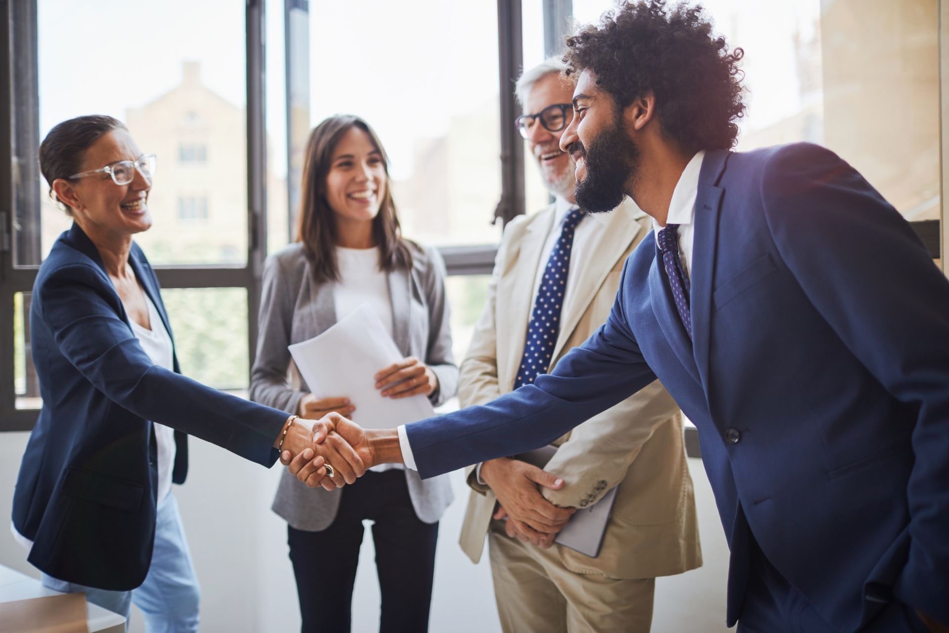 A group of business people are shaking hands in an office.