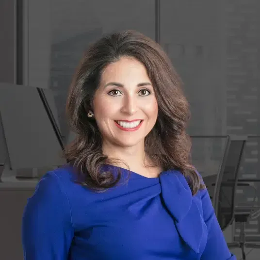 A woman in a blue dress is smiling for the camera.