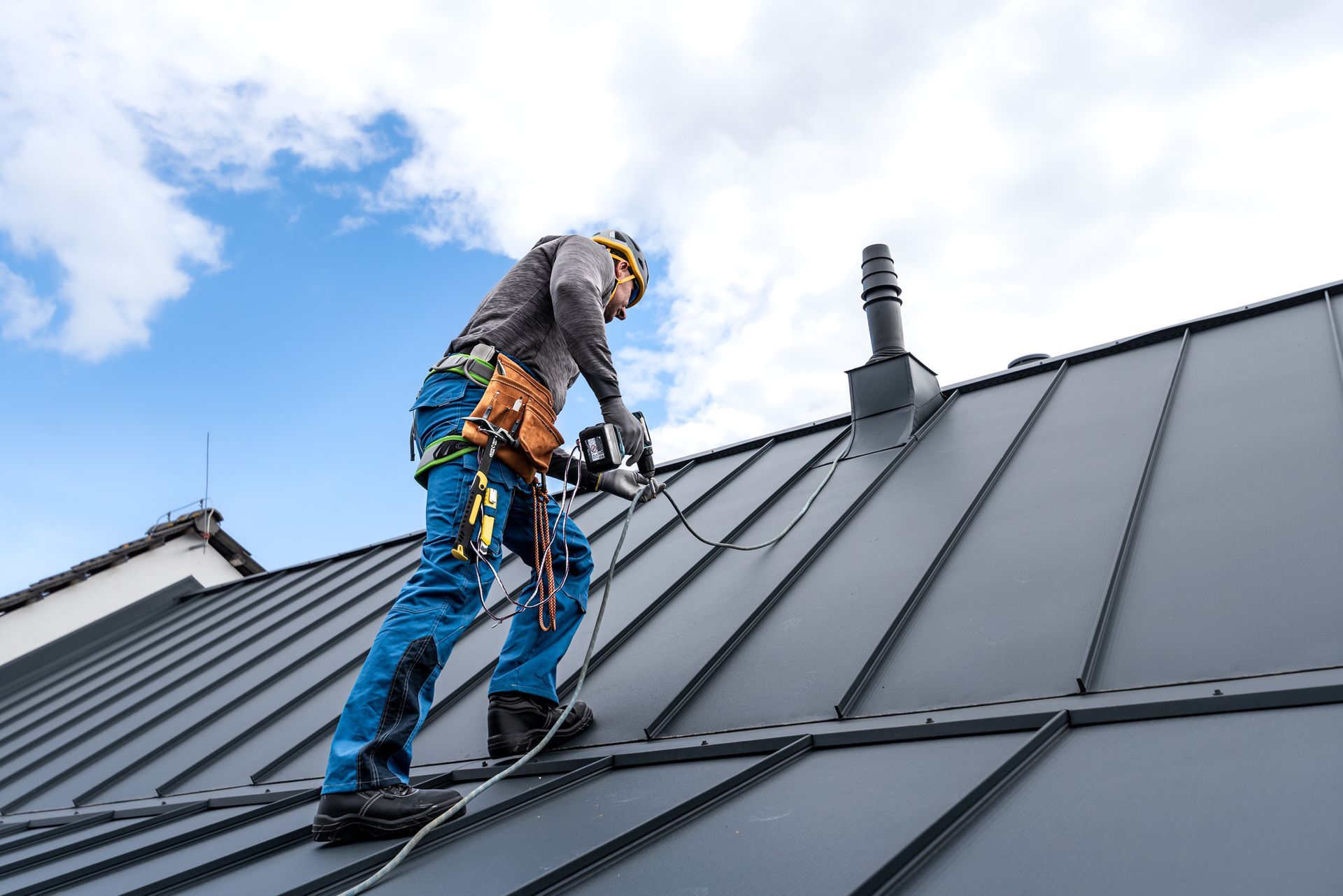 A man is standing on top of a metal roof.