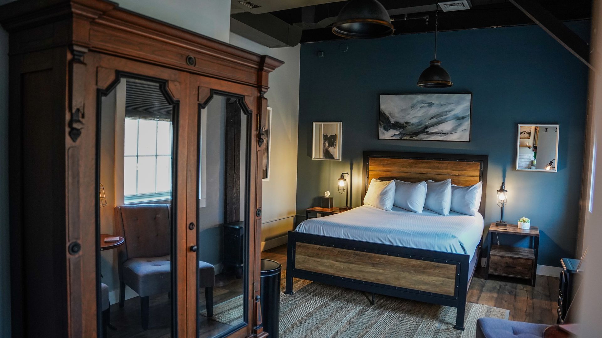 A bedroom with a bed , wardrobe , nightstand and mirrors.
