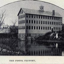 A black and white photo of a large building next to a body of water.