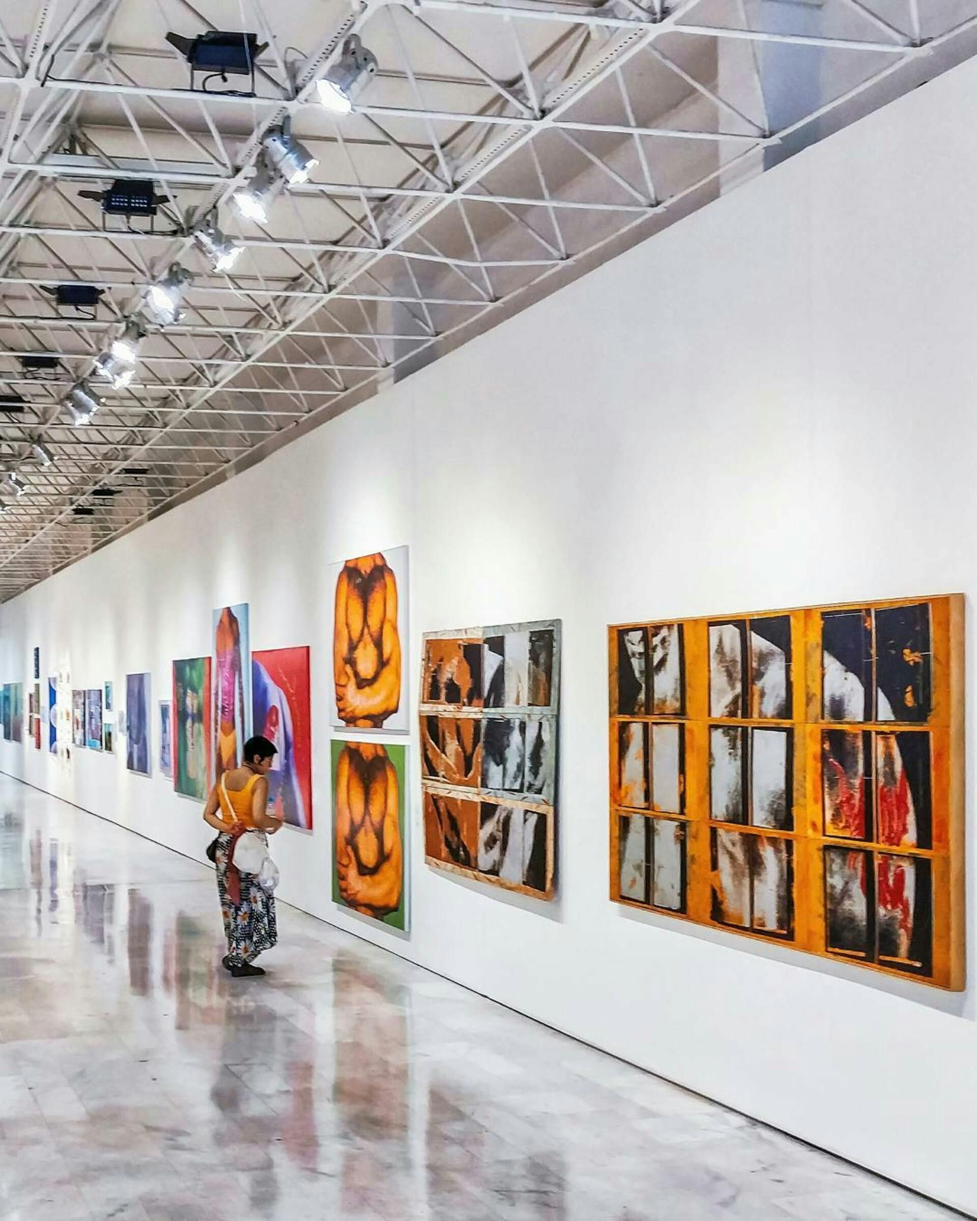 A man is walking down a hallway with paintings on the wall
